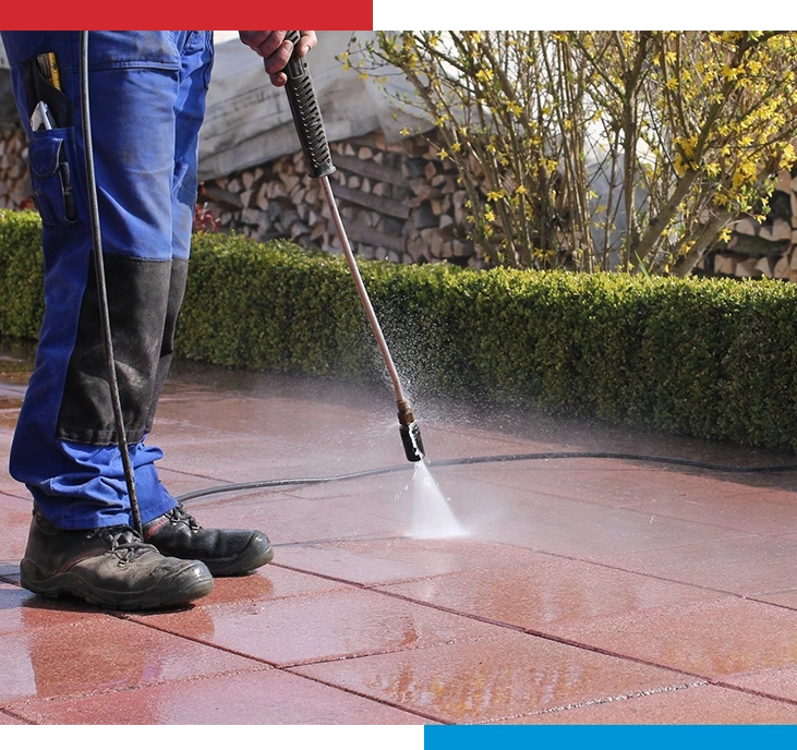 A person using a power washer on the ground.