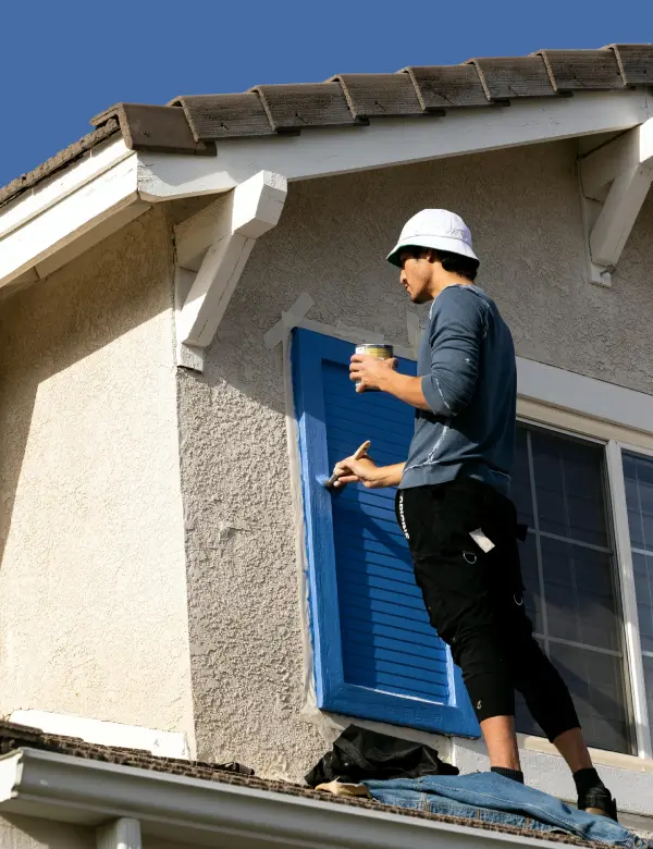 A man in white hard hat standing on the side of a house.